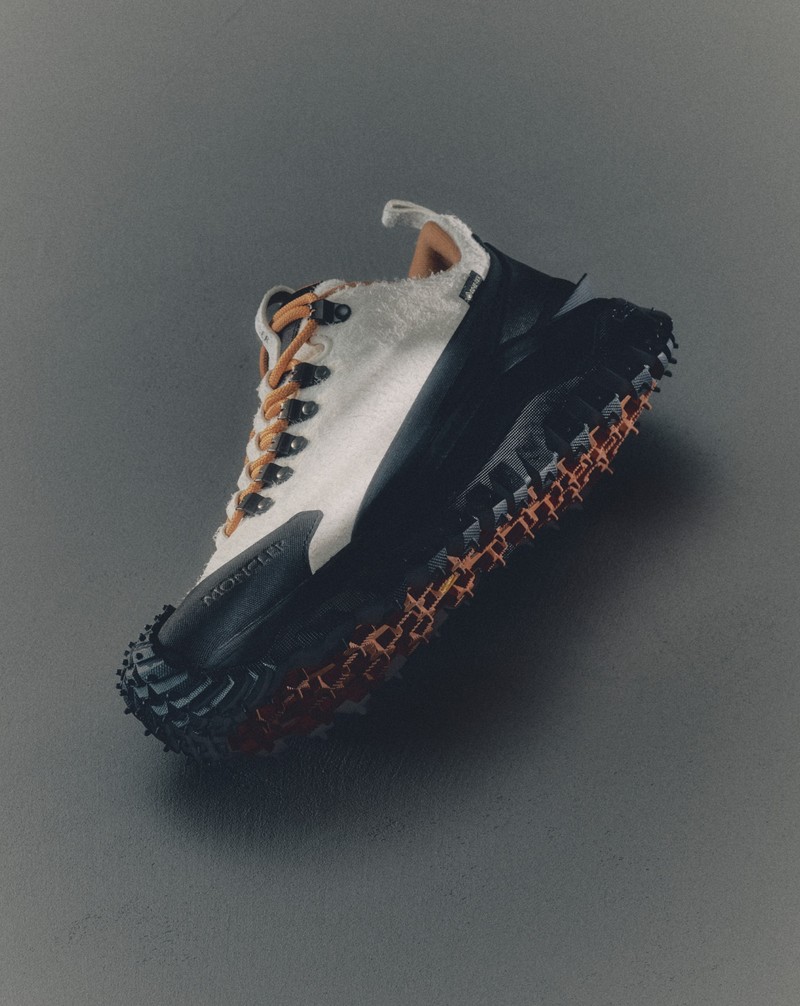 Moncler white technical sneaker with black sole and orange details.