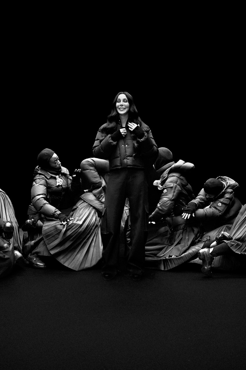 Moncler Re/Icons 2026, behind the scenes in black and white: Grace Jones in a glossy down jacket with the cast. 