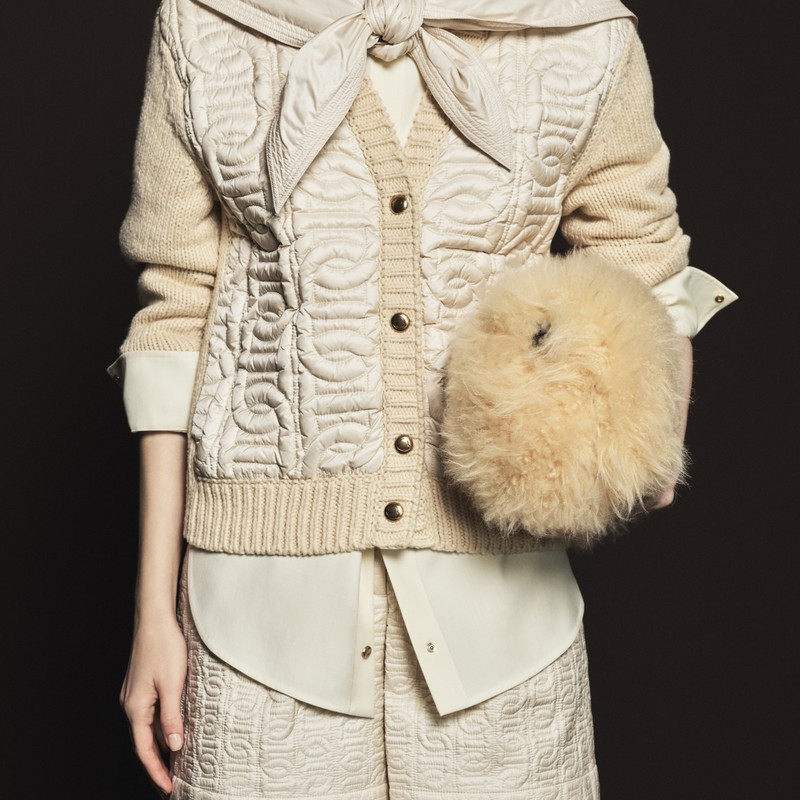 Moncler Pre-Fall 2026 womenswear: brown velvet down jacket worn over a light-blue hooded jacket and a checked skirt