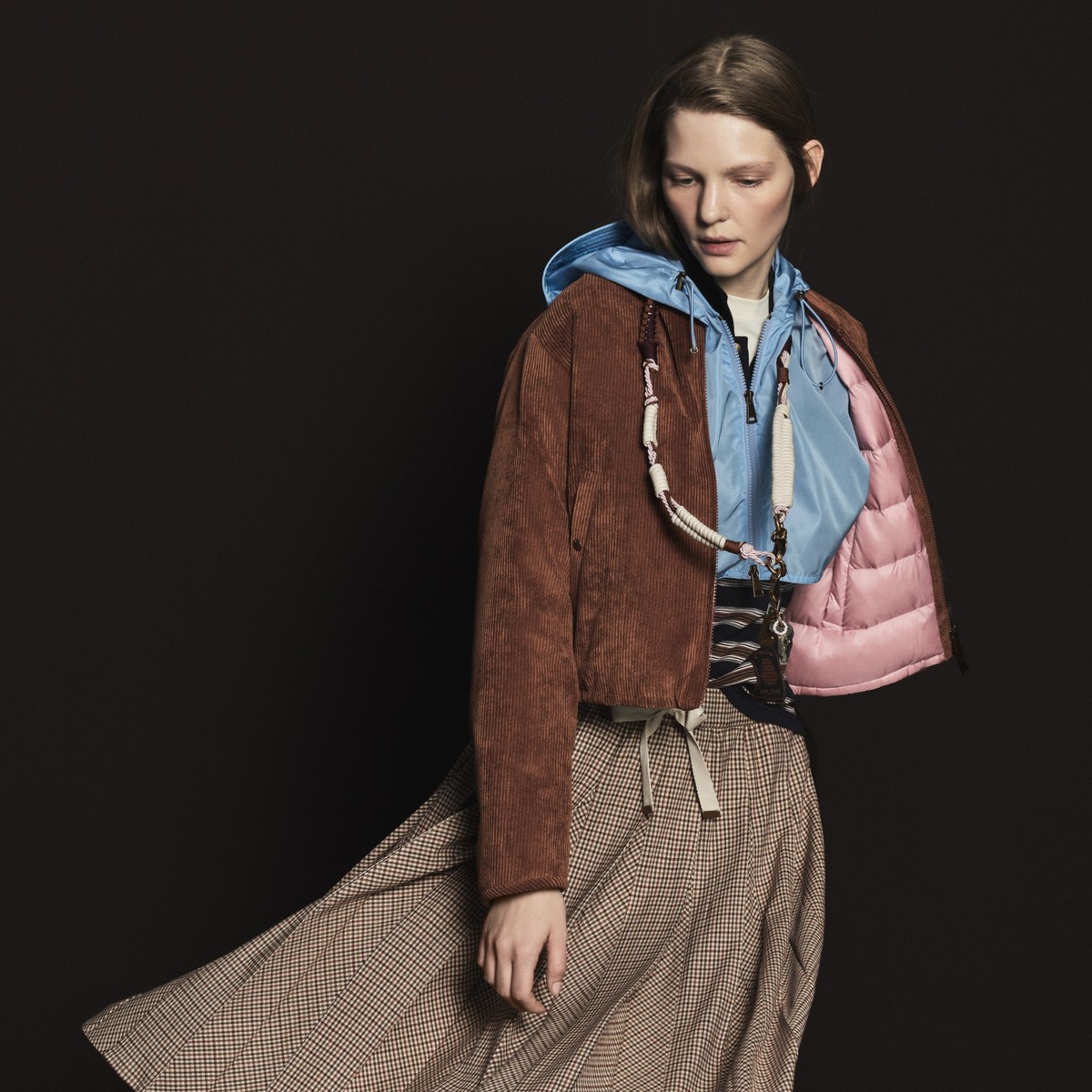 Moncler Pre-Fall 2026, collection femme : doudoune en velours marron sur veste bleu clair à capuche et jupe à carreaux