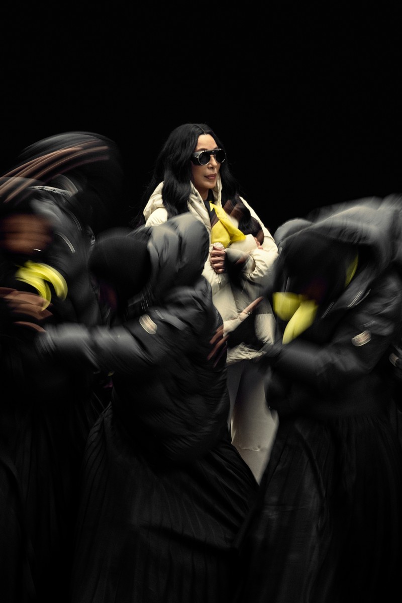 Moncler Re/Icons 2026, Pioneers in Moncle. Dark suits and mirrored sunglasses, long down coat.