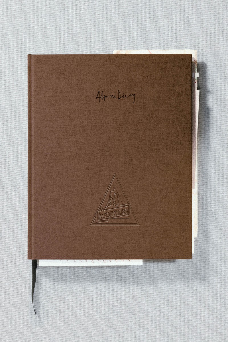 Moncler、The Alpine Diary：表紙にモノクロの花のイラストをあしらったブラウンのクロス装丁の本。