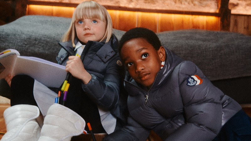 Moncler Fall/Winter 2026 children's clothing and coats. Grey down jackets, dark trousers and white snow boots. 