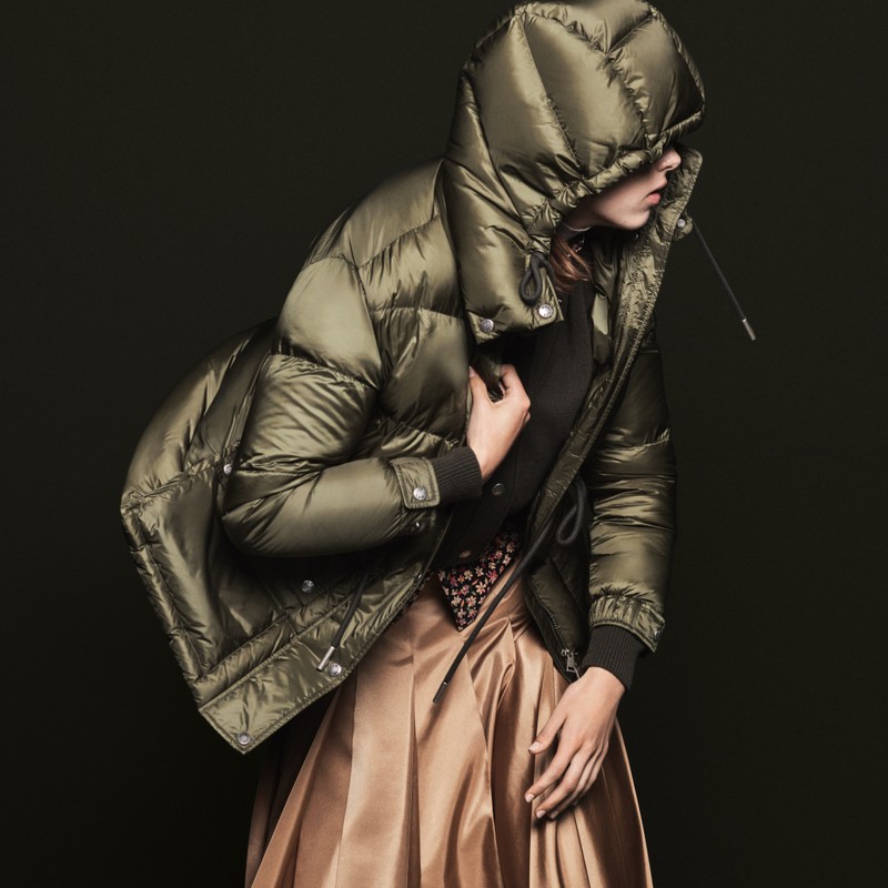 Moncler Oberbekleidung für Damen. Glänzende olivgrüne Kapuzendaunenjacke, geblümtes Top, karamellfarbener Satin-Faltenrock.